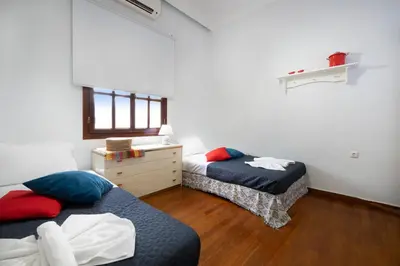 a bedroom with two beds and a dresser and a window at Clio Townhouse in Chania Town