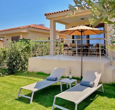 two chairs and an umbrella in the yard of a house at Terra Blue Suites - Dimitra in Kalyves