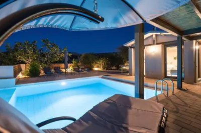 a swimming pool with a table and chairs and an umbrella at Natura Hill Villa I Sea View in Kounoupidhianá