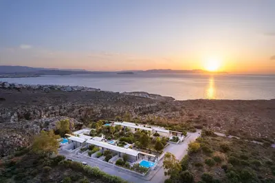 an aerial view of a house with the sun setting over the water at Natura Hill Villa I Sea View in Kounoupidhianá