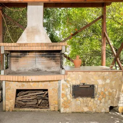 an outdoor oven with a stone fireplace with a roof at liofito village house in Pemónia