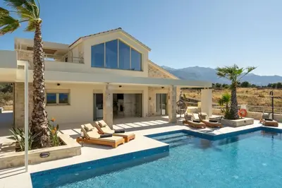 a villa with a swimming pool and palm trees at Villa Athena - Crete Pickleball Paradise in Vamos