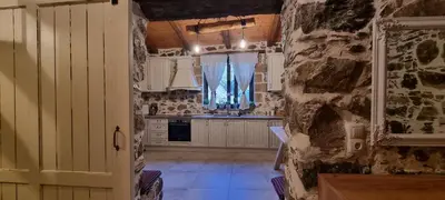 a kitchen with white cabinets and a stone wall at Mesavlia Traditional Stone House in Mesávlia
