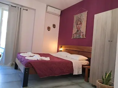 a bedroom with a bed with a purple wall at Poppy Beloni in Chania Town