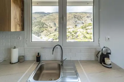 a kitchen counter with a sink and two windows at Avra Sfakia Apartments in Khóra Sfakíon