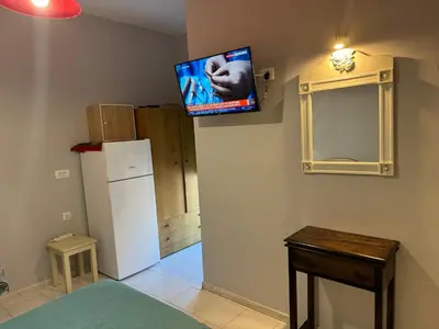 a room with a tv on the wall and a refrigerator at Sofia Rooms in Palaiochóra