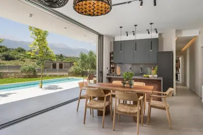 a kitchen and dining room with a table and chairs and a pool at VILLA PETRA PHILIPPOS heated pool optional in Khámbatha