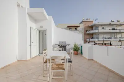 a white apartment with a table and chairs on a balcony at City Apartment with heated rooftop Pool in Chania Town