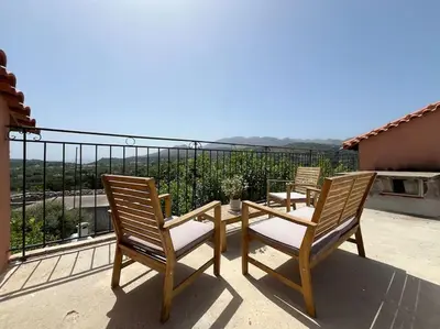 three chairs and a table on a balcony at Vrysses Lodge Michael Stelianos in Vryses