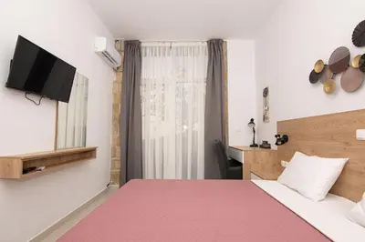 a hotel room with a bed with a pink blanket at Rikanthos Stone Sea View Apartment ΙΙ in Kissamos