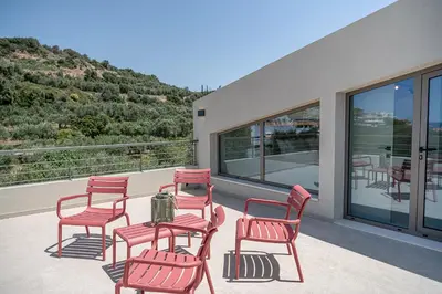a group of red chairs and a table on a balcony at Seaview villa with pool in nature next to Platanias in Plataniás