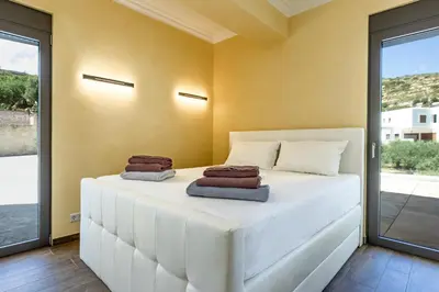 a bedroom with a white bed with towels on it at Naruto Villas in Kissamos