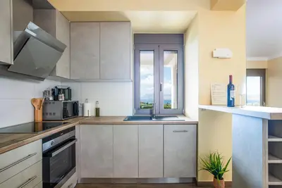 a kitchen with white cabinets and a sink and a window at Naruto Villas in Kissamos
