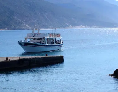 a boat in the water next to a dock at Harbour Studios And Apartments in Palaiochóra