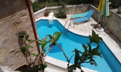 a small swimming pool with a chair and an umbrella at Charmante maison crétoise à Embrosneros in Embrósneros
