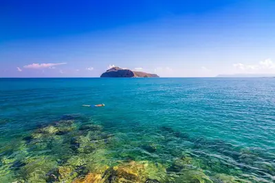 a person swimming in the ocean near a rock formation at Modern Dream Apartment in Plataniás
