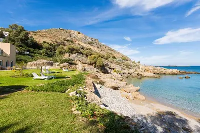 a beach with some chairs and the water at Harmony Villa in Chania Town