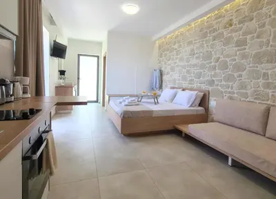 a bedroom with a bed and a stone wall at Studios Rosmari in Áyioi Pándes