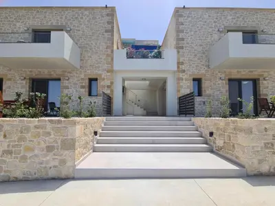 a house with a stone wall and stairs at Studios Rosmari in Áyioi Pándes
