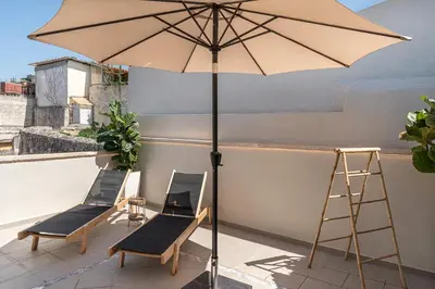 a patio with chairs and an umbrella on a roof at Steki Luxury Room 3 in Chania Town