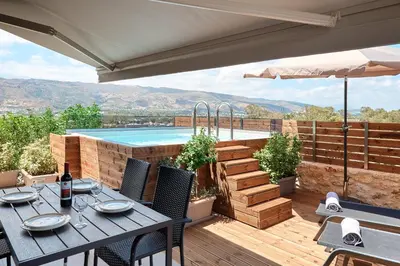 a patio with a table and a swimming pool at Thearia villa II private heated hydromassage pool in Souda