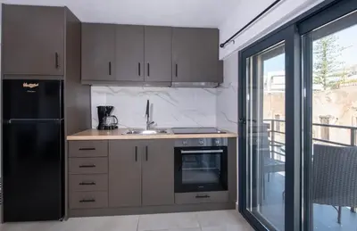 a kitchen with brown cabinets and a black refrigerator at Halepa Apartment's in Chania in Chania Town