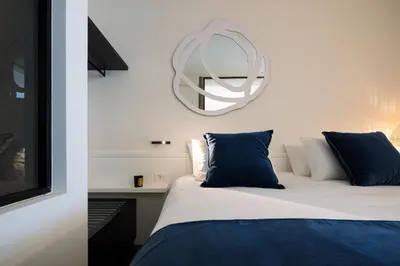 a bedroom with a bed with blue pillows and a mirror at Sea Path III Chania city Center luxury Suites in Chania Town