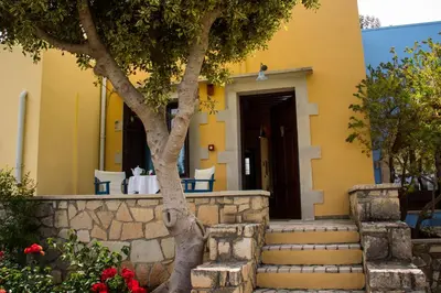 a yellow house with stairs and a tree at Heliopetra studios, small village near beaches in Douliana