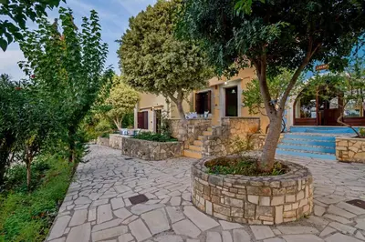 a stone walkway with a tree in front of a house at Heliopetra studios, small village near beaches in Douliana