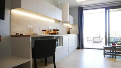 a kitchen with white cabinets and a counter with a table at Amour Relax Hotel in Almirida