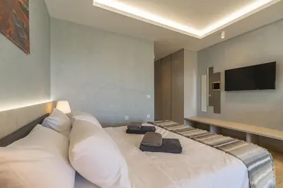 a bedroom with a large white bed with a flat screen tv at Amour Relax Hotel in Almirida