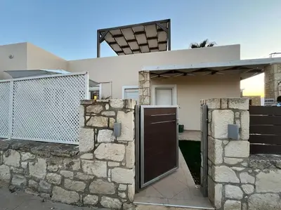 a house with a gate and a stone wall at Colibri seafront villa with pool in Nopíyia