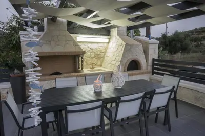 a patio with a table and chairs and a fireplace at Villa-Azalea in Almirida