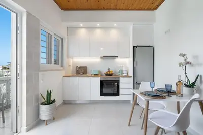 a kitchen with white cabinets and a table and chairs at Maestro House in Chania Town