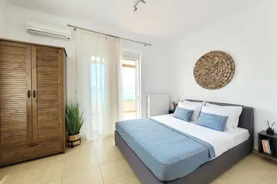 a bedroom with a bed and a large window at Everlane Seaview Villa in Arménoi