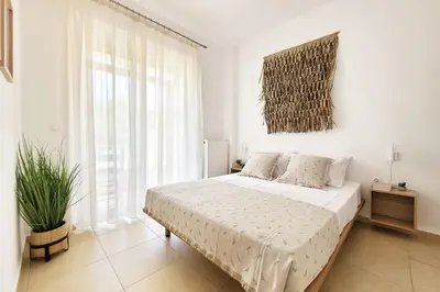 a white bedroom with a bed and a large window at Everlane Seaview Villa in Arménoi