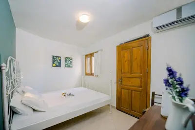 a white room with a bed and a wooden door at Nature stone retreat between Balos & Elafonisi beach, contactless check-in, Mouri Nature House in Mouríon
