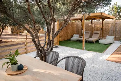a patio with a table and chairs and a tree at Falasarna Caravans in Falasarna
