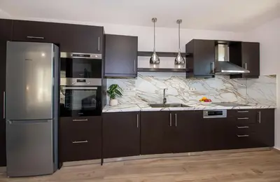 a kitchen with brown cabinets and a stainless steel refrigerator at Iasmos in Sfakiá