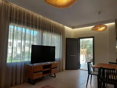 a living room with a flat screen tv and a table at VENTO villa neriana in Khainderianá