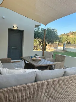a patio with a table and couches and a table and chairs at VENTO villa neriana in Khainderianá