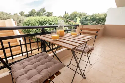 a balcony with a wooden table and two glasses of orange juice at Ibis Apartments Chania,close to the beach in Chania Town
