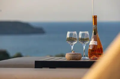 two wine glasses and a bottle of wine on a table at Theo Luxury Villas With Sea View in Agia Marina Nea Kydonias