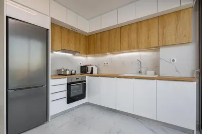a kitchen with white cabinets and a stainless steel refrigerator at Theo Luxury Villas With Sea View in Agia Marina Nea Kydonias