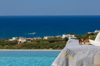 a pair of sunglasses sitting on a chair next to a pool at Theo Luxury Villas With Sea View in Agia Marina Nea Kydonias