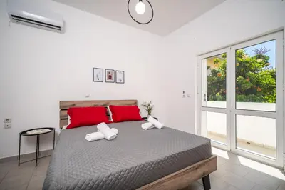 a bedroom with a bed with red pillows and a window at Viola Apartment in Kissamos