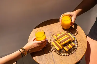 two people holding glasses of orange juice and a plate of cheese at Viola Apartment in Kissamos