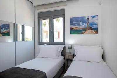 two beds in a room with two windows at Casa Platanias Bridge in Plataniás