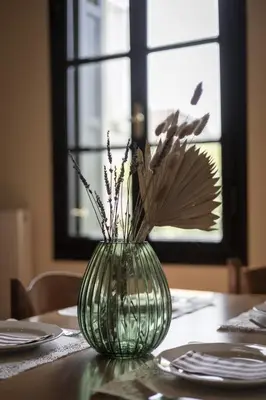 a green vase with flowers in it on a table at Sundial Lodge in Chania Town