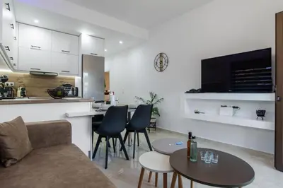 a living room and kitchen with a couch and a table at Casa Manou - Kalyves beach in Kalyves